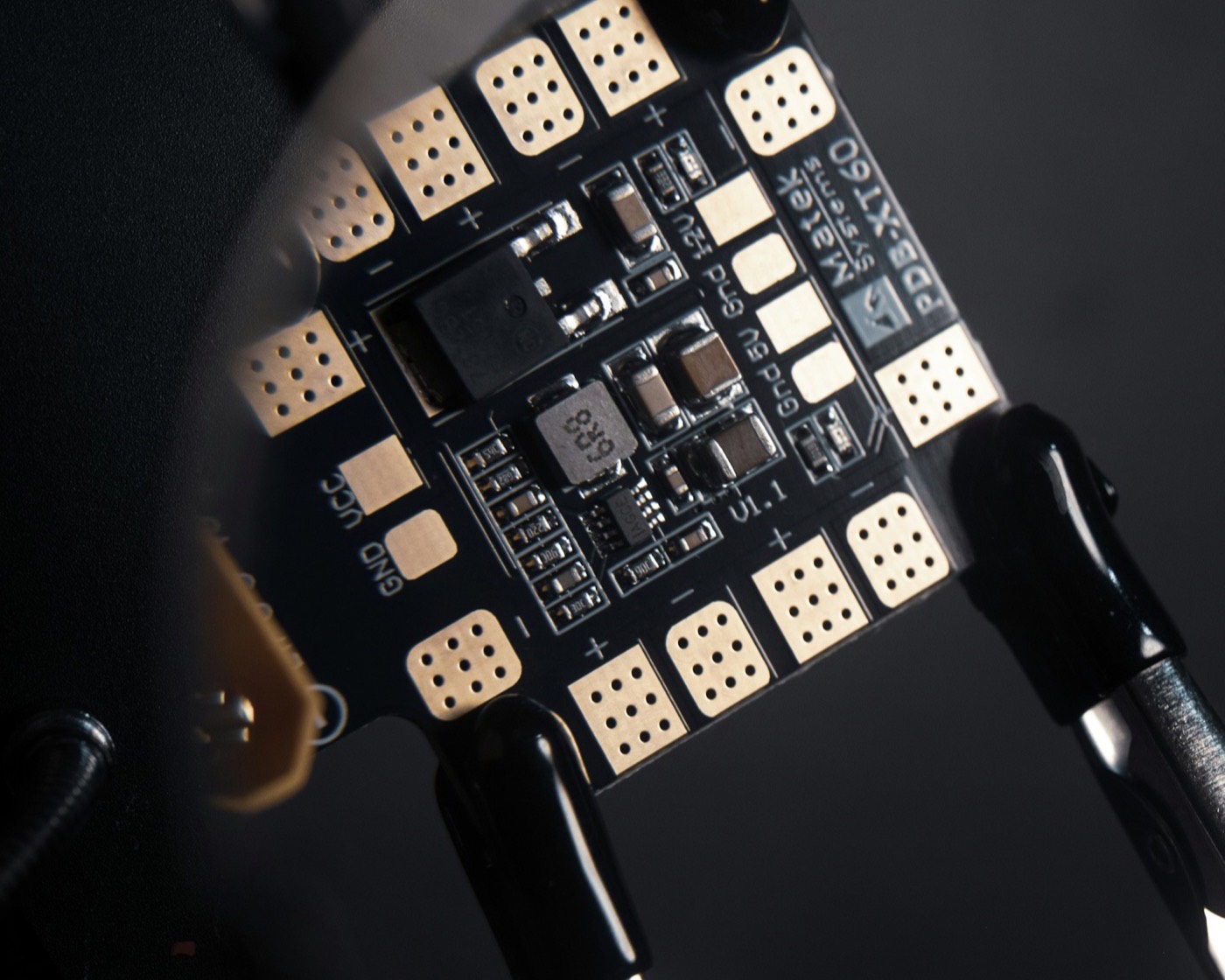 A circuit board held in clamps, ready to be worked on